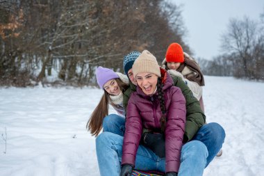 Aile, karlı tepede kış kızağı kayarken eğleniyor. Kış eğlencesi.
