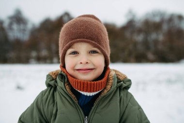 Soğuk kış günlerinde dışarıda duran sevimli bir çocuğun portresi. Karlı manzara.