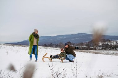 Ebeveynler ve çocuklar kızak macerasına başlıyorlar. Kış aile aktivitesi.