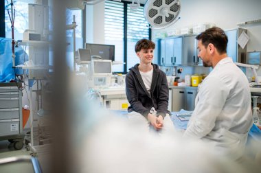 Genç çocuk, olumlu sağlık haberleri aldıktan sonra tıbbi danışmanlık sırasında gülümsüyor.