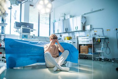 Endişeli genç hasta hastanede tek başına oturuyor, zihinsel sağlık sorunları ve anksiyete sorunlarıyla boğuşuyor..