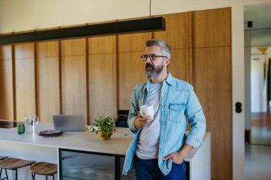 Ev ofisinden bilgisayarda çalışan, kahve içen bir adam..