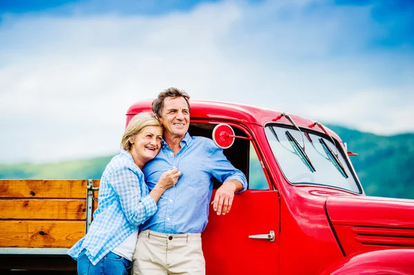 Coppia senior con auto rossa — Foto Stock