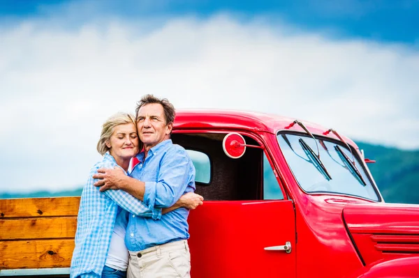 Pareja mayor con coche rojo — Foto de Stock