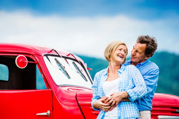 Äldre par med röd bil — Stockfoto