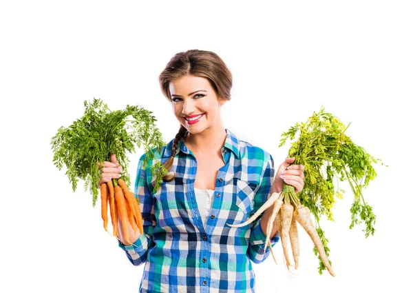 Jonge vrouw met wortelen en peterselie — Stockfoto