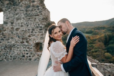 Gelin ve damat dans ediyor, birbirlerine bakıyorlar. Dışarıda yıkıntıların yanında duran güzel bir çift..