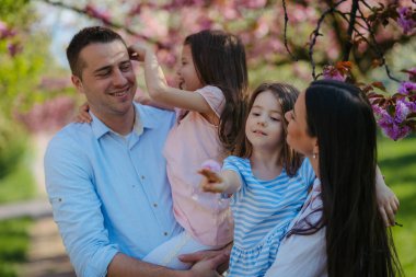 Bahar doğasında dışarıda duran iki kızı olan genç bir aile..
