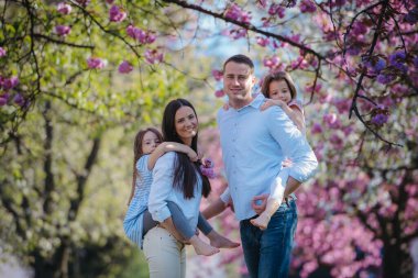 Bahar doğasında dışarıda duran iki kızı olan genç bir aile..