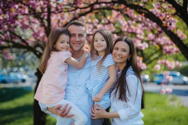 Bahar doğasında dışarıda duran iki kızı olan genç bir aile..