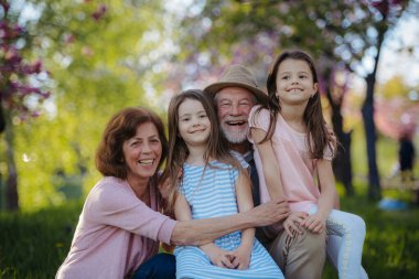 Büyükbabalar torunlarıyla parkta vakit geçiriyorlar. Bahar mevsimi.
