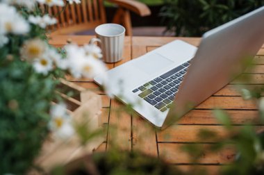 Laptop ve kahve baharda ahşap bahçe masasında.