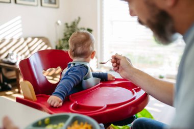 Bakıcı baba yemek saatinde bebeğini besliyor..