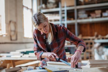 Marangozluk atölyesinde ürünleri üzerinde çalışan kadın marangoz. Küçük işletme kavramı.