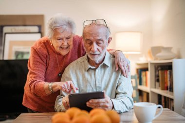Kıdemli çift tabletle çalışıyor, rezervasyon yaptırıyor ya da internetten alışveriş yapıyor. Dijital okuryazarlık.