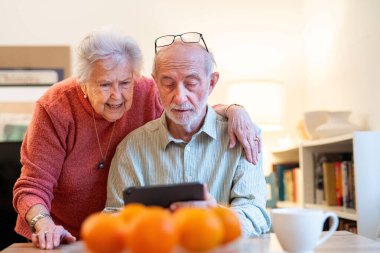 Kıdemli çift tabletle çalışıyor, rezervasyon yaptırıyor ya da internetten alışveriş yapıyor. Dijital okuryazarlık.