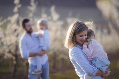 Bahar aile portresi. Çiçek açan meyve bahçesinde iki küçük çocuk..