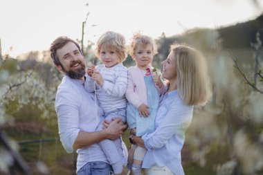 Bahar aile portresi. Çiçek açan meyve bahçesinde iki küçük çocuk..