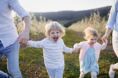 Çiçek açan meyve bahçesinde iki küçük çocuklu bir aile. Bahar mevsimi.