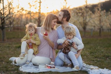 Aile bahar doğasında piknik yapıyor, piknik battaniyesinde dinleniyor. İlkbahar konsepti.