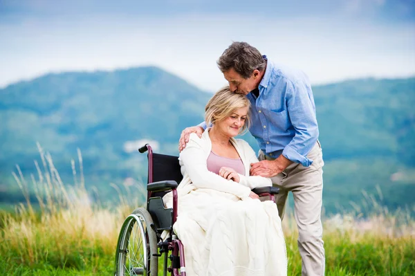 Uomo con donna sulla sedia a rotelle — Foto Stock