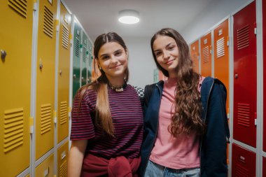 Genç öğrenciler okul koridorunda renkli dolapların yanında takılıyor..