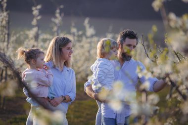 Bahar aile portresi. Çiçek açan meyve bahçesinde iki küçük çocuk..