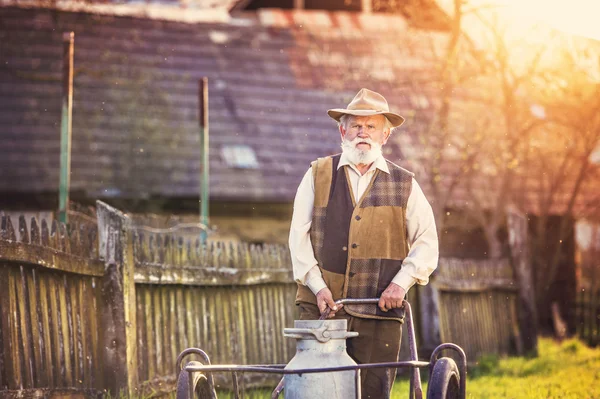 Senior man with milk kettle — Stock Photo, Image