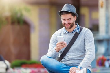Genç adam akıllı telefon kullanıyor.