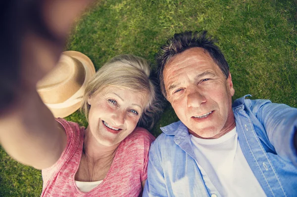 Senior couple lying on grass — Stock Photo, Image