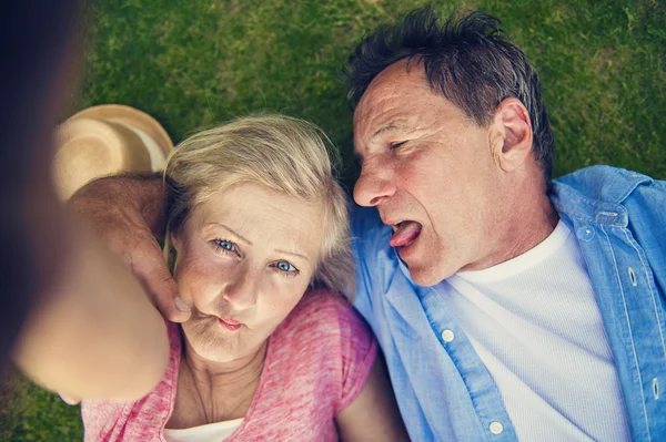 Äldre par liggande på gräs — Stockfoto