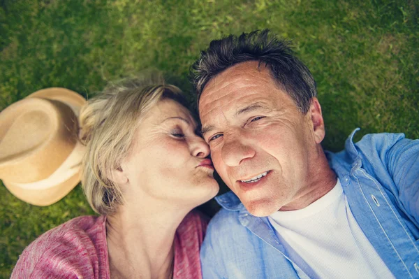 Senior par som ligger på gress – stockfoto