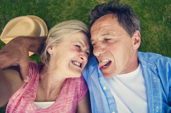 Senior par som ligger på gress – stockfoto