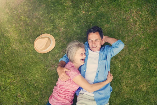 Pareja mayor acostada en la hierba — Foto de Stock