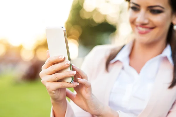 Empresária com smartphone no parque — Fotografia de Stock