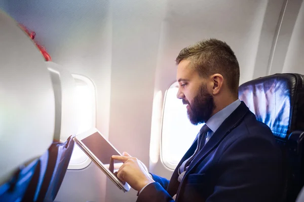 Businessman in airplane with tablet — Stock Photo, Image