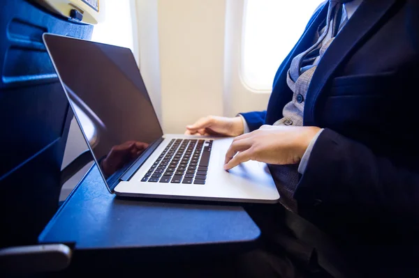 Zakenman in vliegtuig die op laptop werkt — Stockfoto