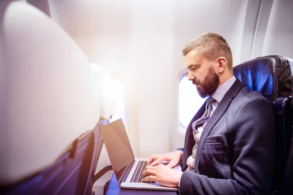 Uomo d'affari in aereo con computer portatile — Foto Stock