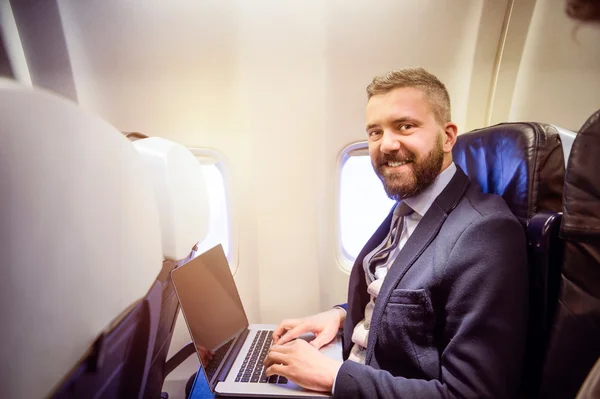 Businessman in airplane with laptop — Stock Photo, Image