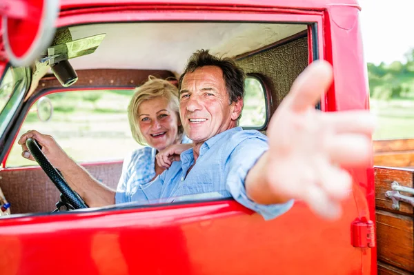 Coppia di anziani in auto rossa — Foto Stock