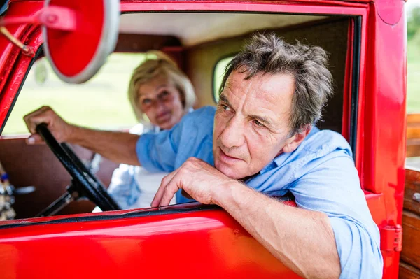 Coppia di anziani in auto rossa — Foto Stock