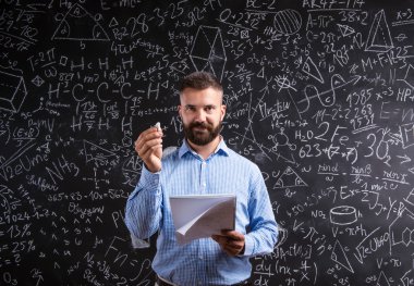 Teacher with notebook against big blackboard with symbols and fo