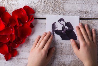 Man holding his and his girlfriends photo. Rose petal heart.