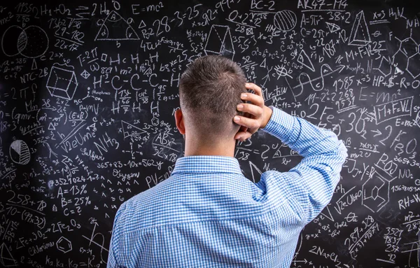 Back view of teacher against big blackboard with mathematical sy — Stock Photo, Image