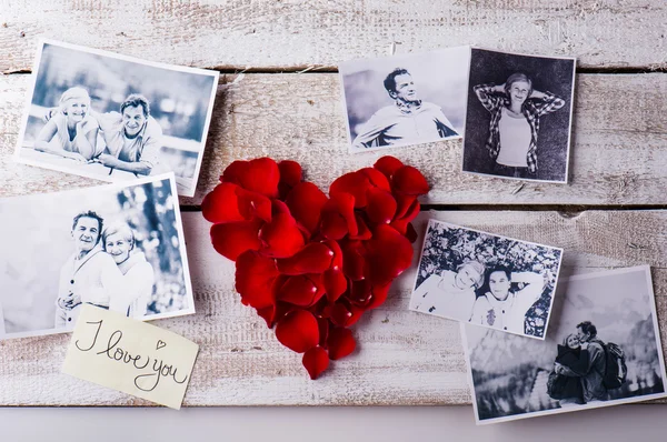 Photos of a couple in love. Red rose petal heart. — Zdjęcie stockowe