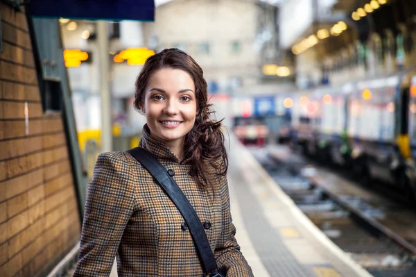 Young woman in brown winter coat waiting on train station — Stockfoto