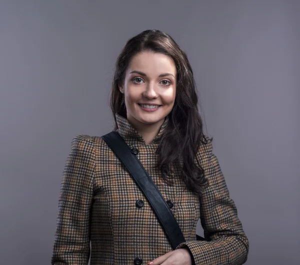 Young woman in checked brown winter coat. Studio shot. — Stock Photo, Image