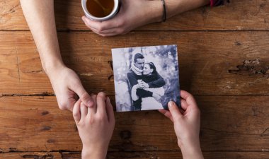 Unrecognizable man holding womans hand. Looking  at their photo. Couple
