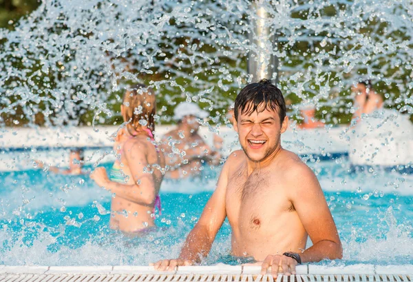 Couple dans la piscine sous la fontaine à éclaboussures. Chaleur estivale . — Photo