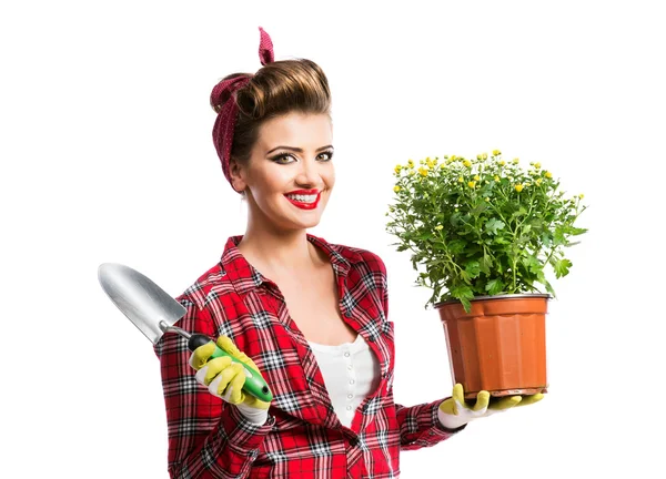 Pin-up girl holding flower pot with yellow daisies and shovel — Stok fotoğraf